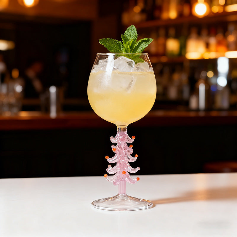 Colorful Christmas tree stemmed glass with beverage and festive decoration