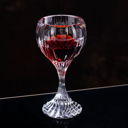Classic cut stemmed glass with red beverage in dark background setting