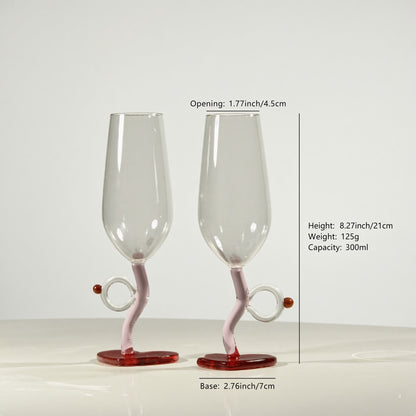 Two clear glass champagne flutes with twisted pink stems and red bases, shown on a light gray background with measurement text and lines indicating dimensions.