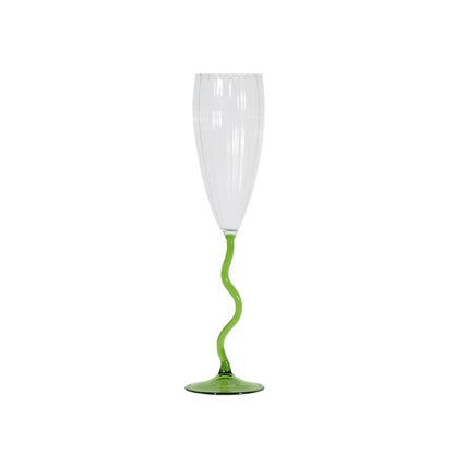 A clear champagne flute with a vibrant green, wavy stem and a matching green circular base, shown against a plain white background.
